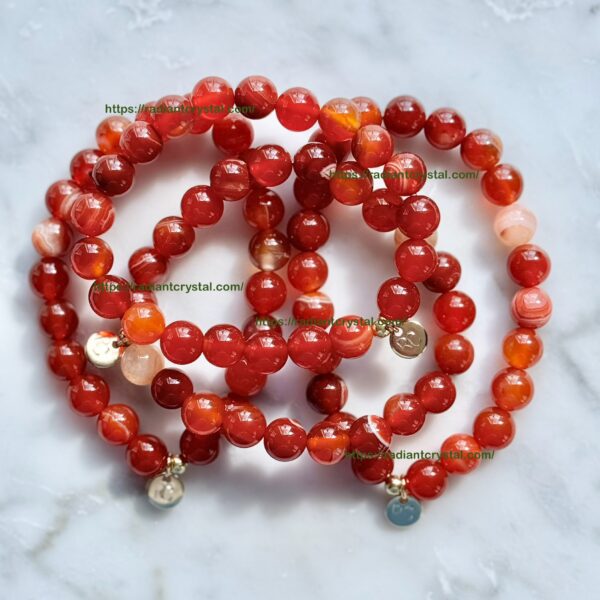 Red carnelian bead bracelets with gold charms.