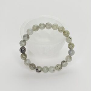 A bracelet of grey and white beads on a clear surface.