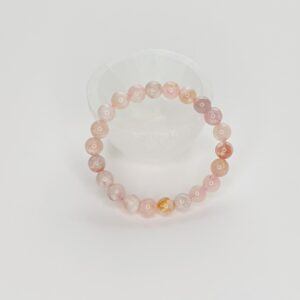 A pink bracelet is sitting on top of a white table.