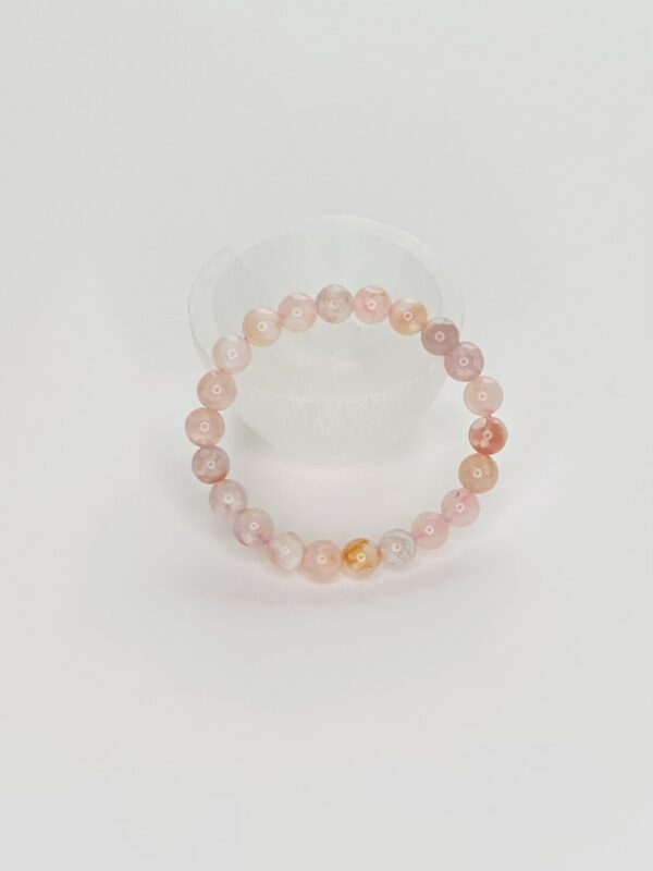 A pink bracelet is sitting on top of a white table.