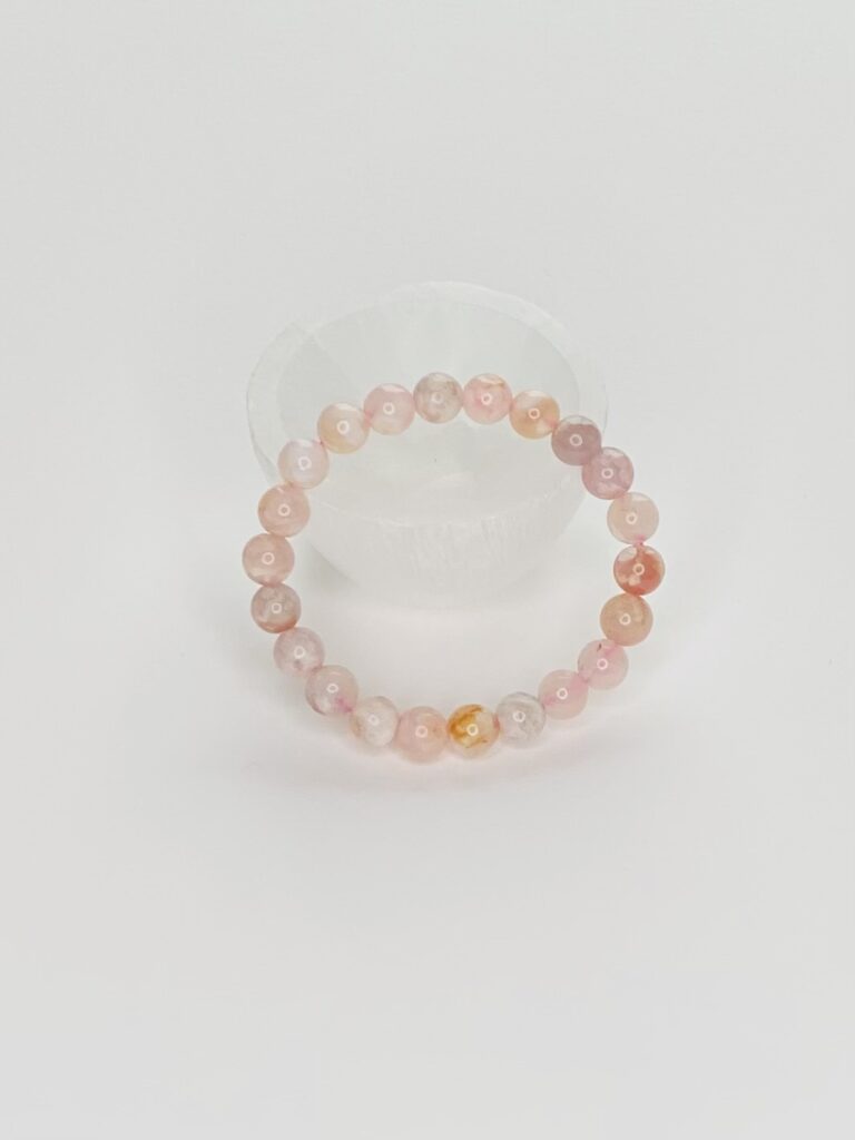 A pink bracelet is sitting on top of a white table.