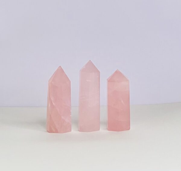 Three pink quartz points on a white surface