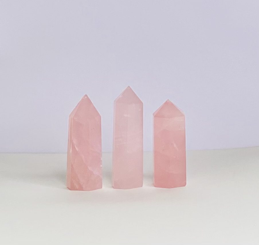 Three pink quartz points on a white surface