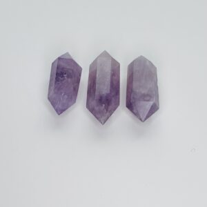 Three amethyst points are sitting on a white surface.