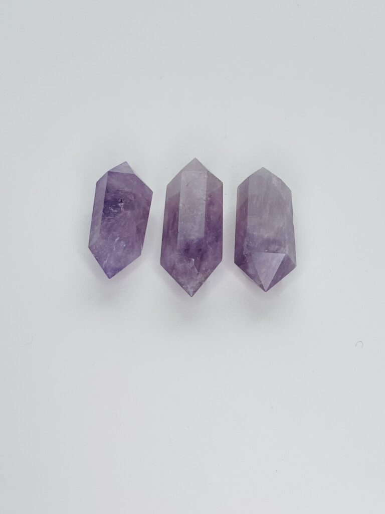 Three amethyst points are sitting on a white surface.