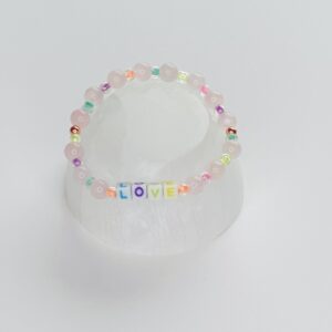 A white plastic cup with a rainbow colored bracelet.