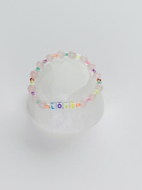 A white plastic cup with a rainbow colored bracelet.