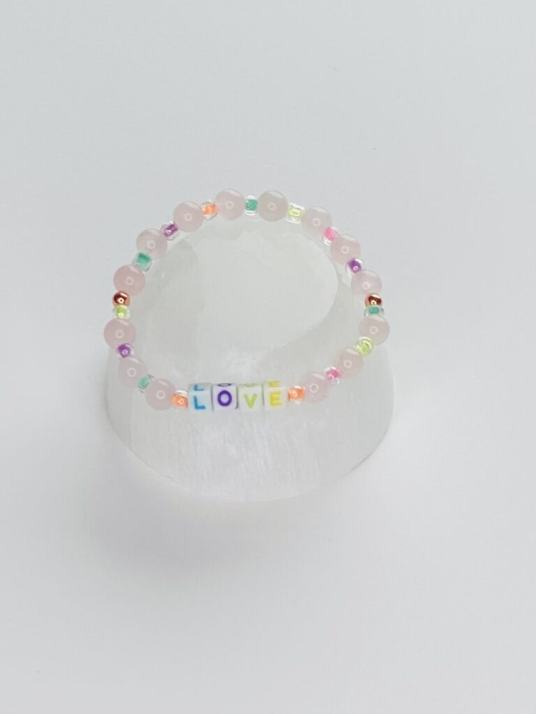 A white plastic cup with a rainbow colored bracelet.