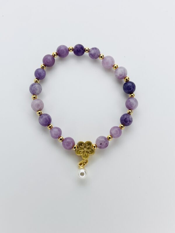 A purple bracelet with gold beads and a white bead.