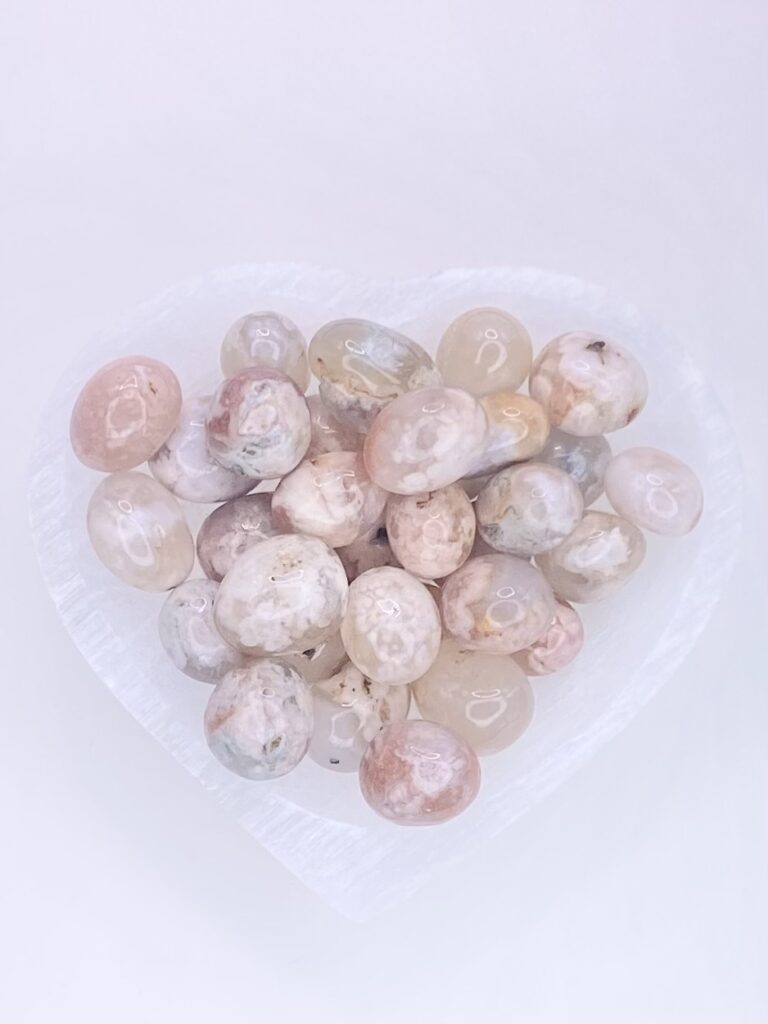 A heart shaped glass bowl filled with pebbles.