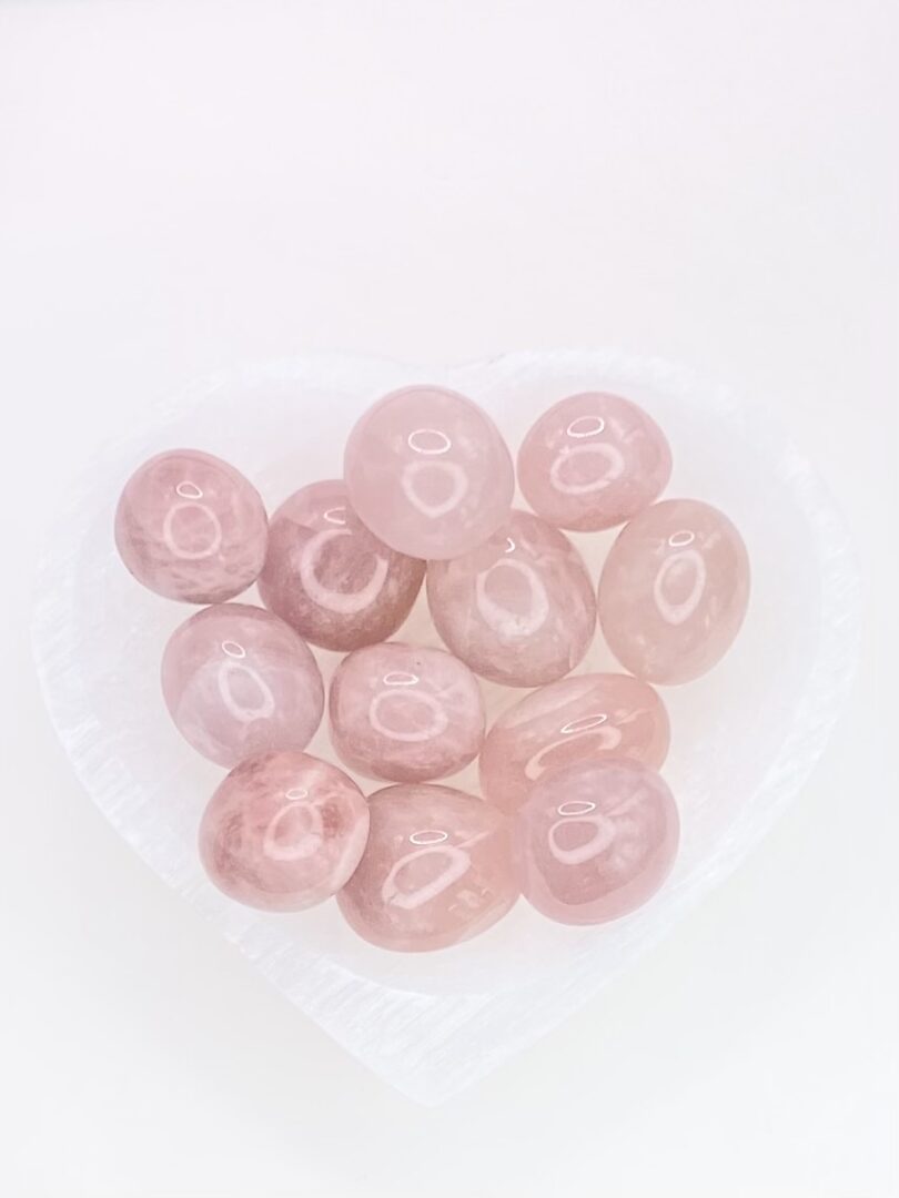 A heart shaped bowl filled with Rose Quartz Tumbled Stones.