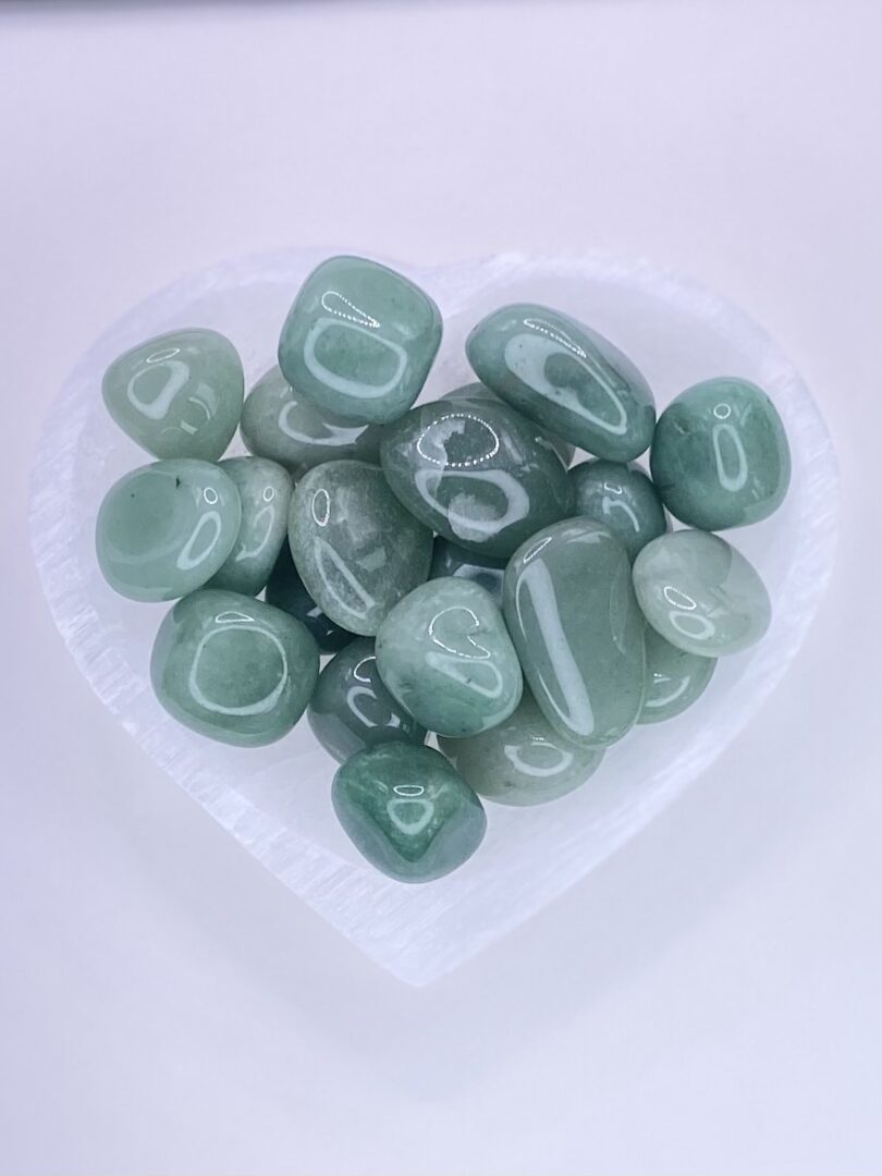 Green aventurine tumbled stones in a heart shaped bowl.