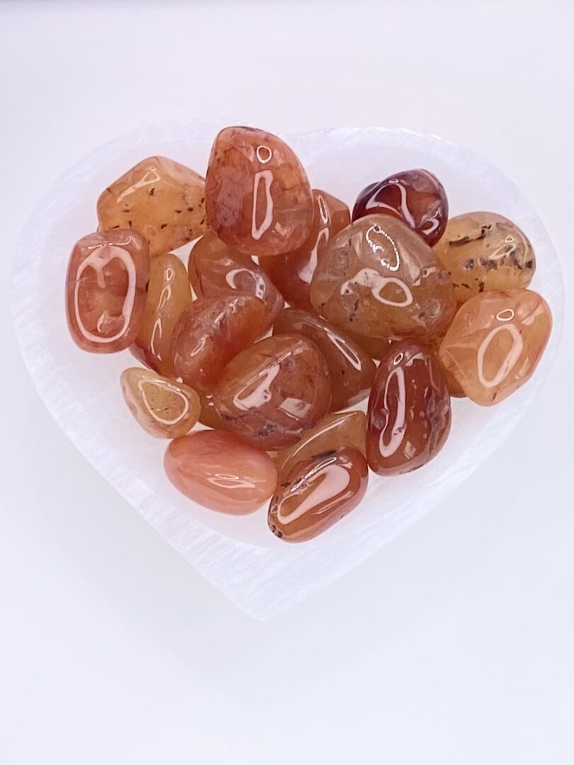 A heart shaped plate filled with Carnelian Tumbled Stones.