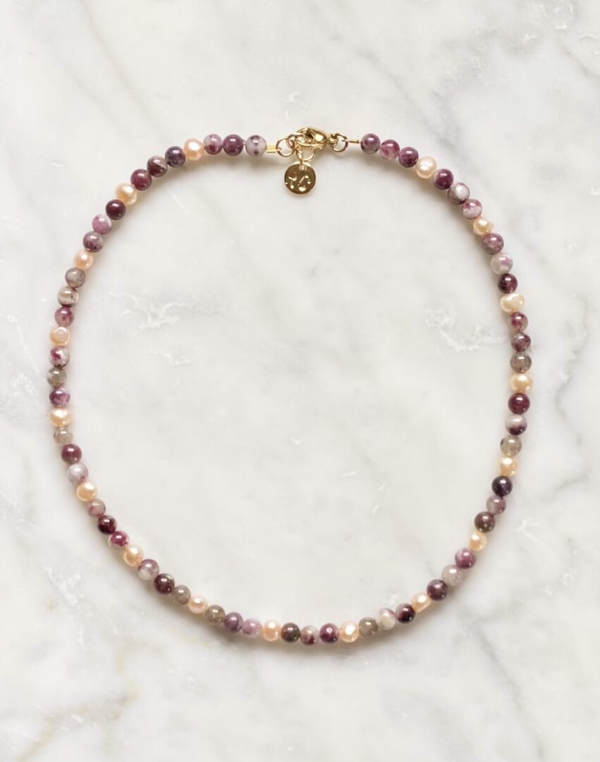 A Plum Blossom Tourmaline & Pearls necklace on a marble table.