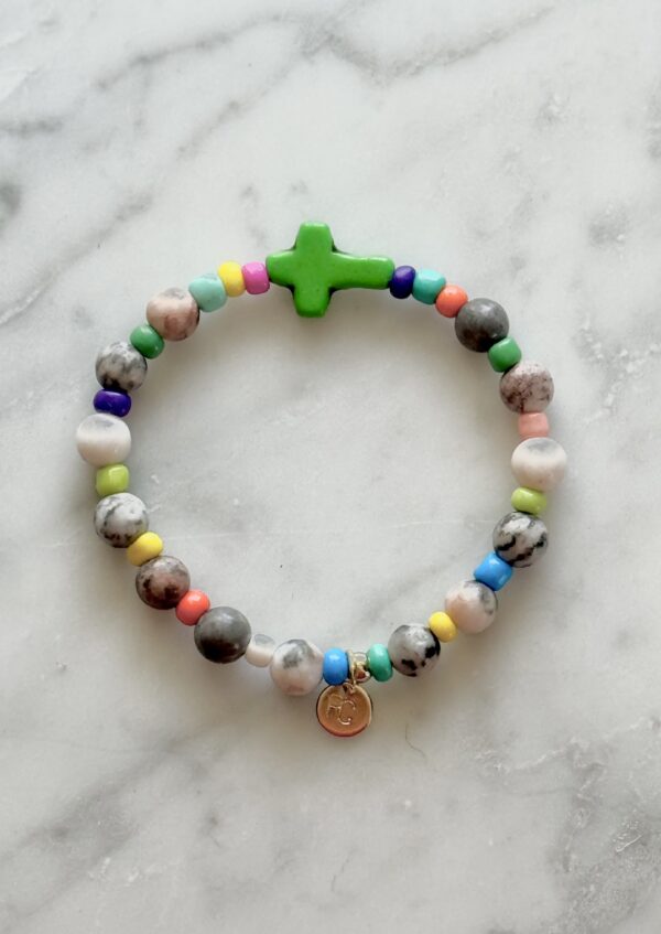 Colorful beaded bracelet with a green cross charm.