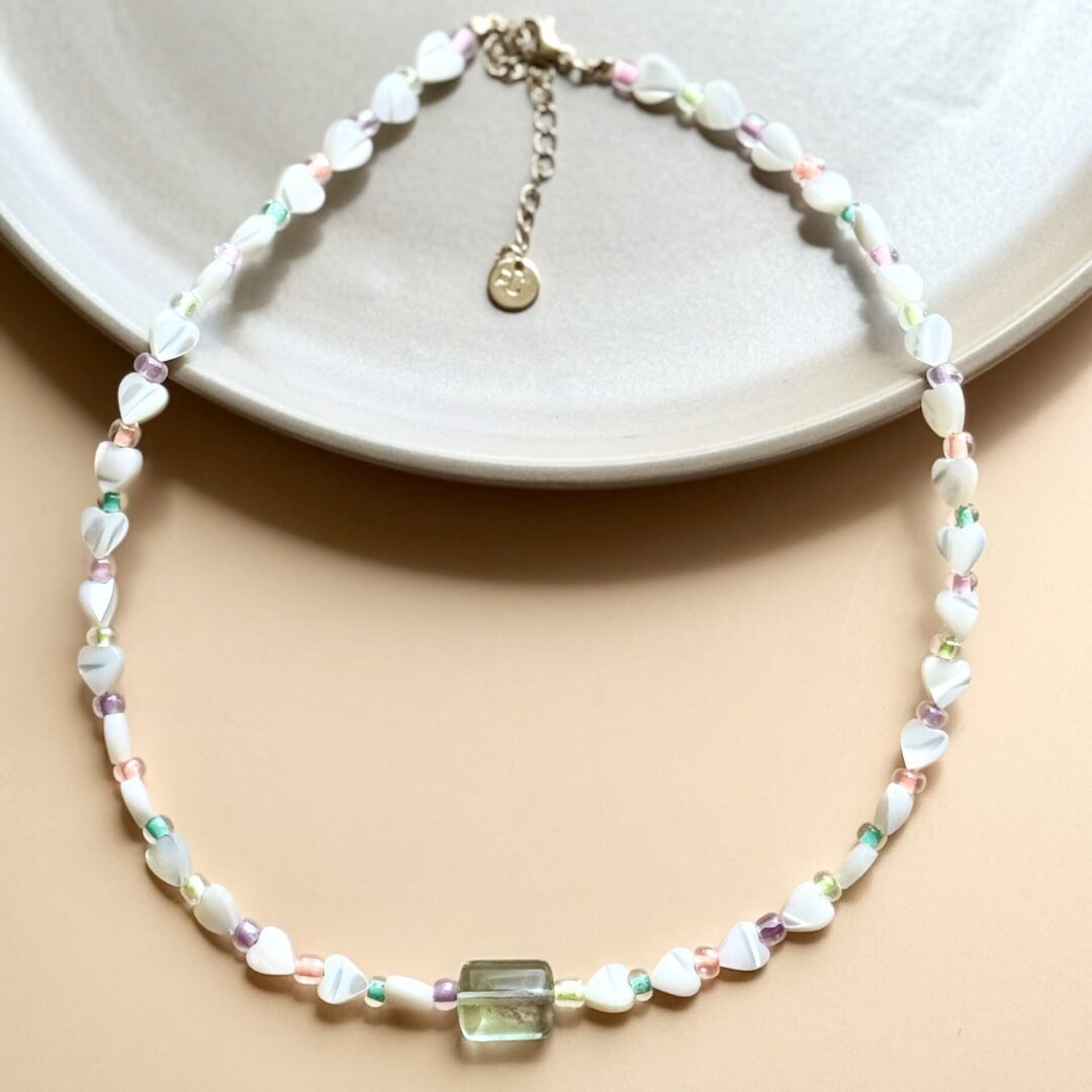 White heart beaded necklace with green charm.