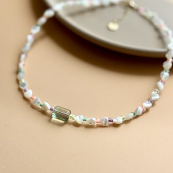 Beaded necklace with green stone charm.