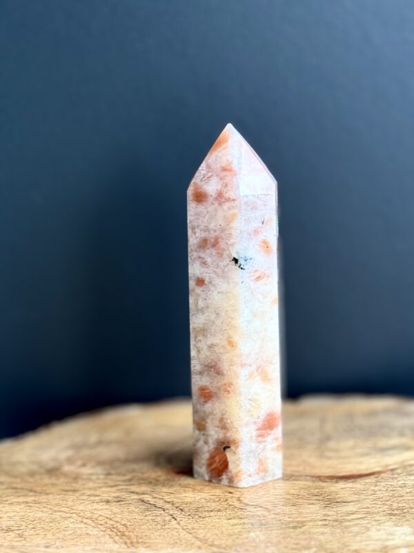 Orange sunstone crystal point on wood.