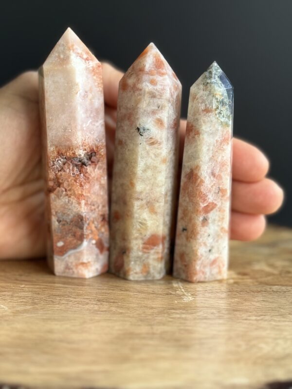 Three sunstone crystal points on wood.