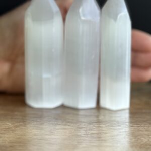 Three white selenite crystal points on wood.