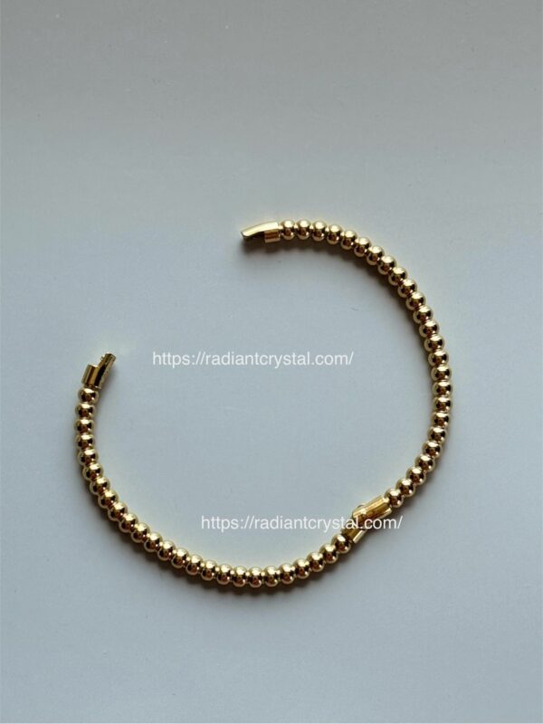 Gold bead bracelet on white background.