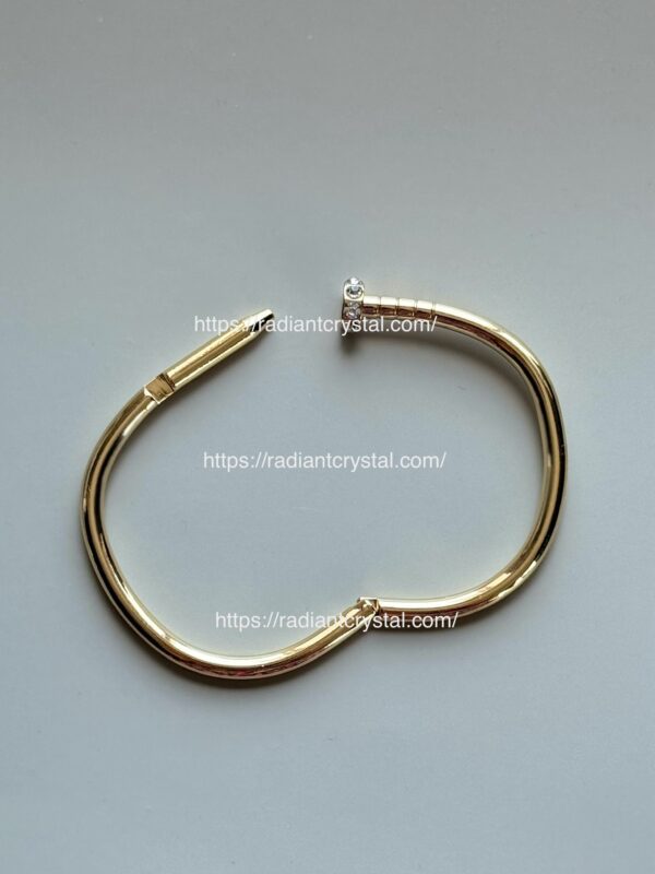 Gold nail-shaped bracelet with diamond.