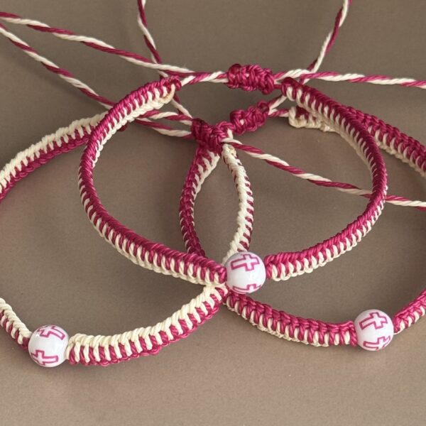 Three pink and white cross bracelets.