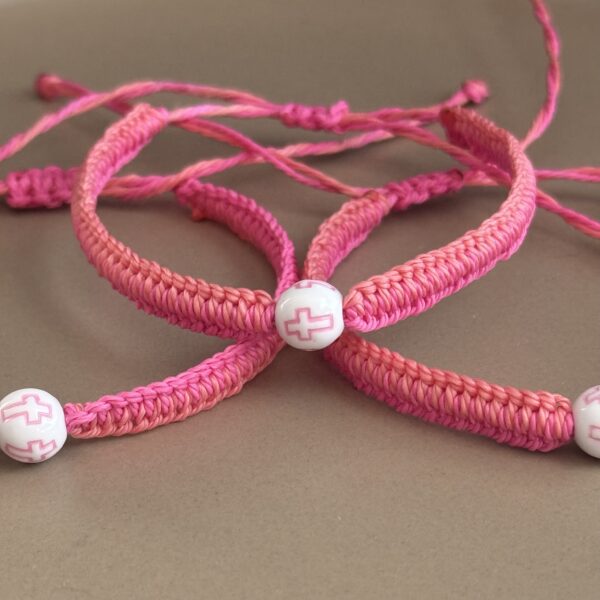 Pink braided bracelets with cross beads.