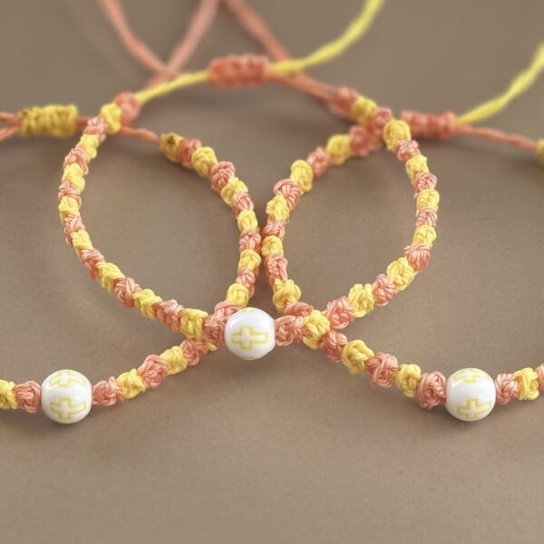 Three yellow and pink prayer bracelets.