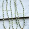 Three green and gold beaded necklaces with cross charms.