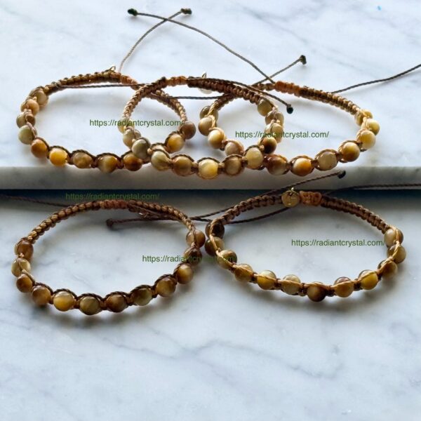 Four brown beaded bracelets on white surface.