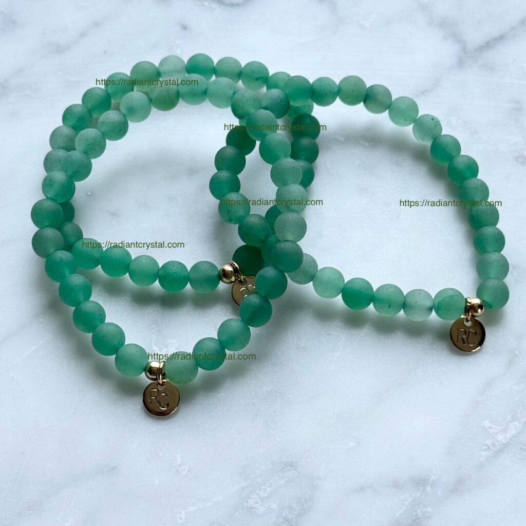 Three green beaded bracelets with gold charms.