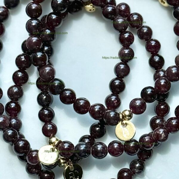 Three garnet bead bracelets with gold charms.