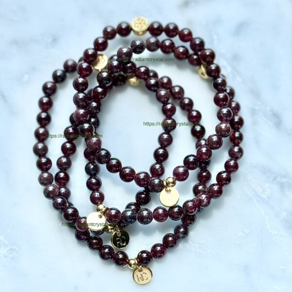 Three garnet beaded bracelets with charms.