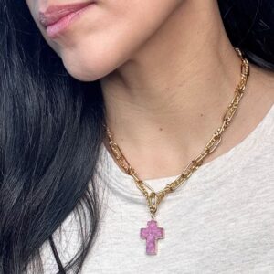 Gold chain necklace with purple cross pendant.