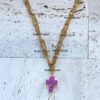 Gold chain necklace with purple cross pendant.