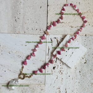 Pink bead necklace on textured surface.
